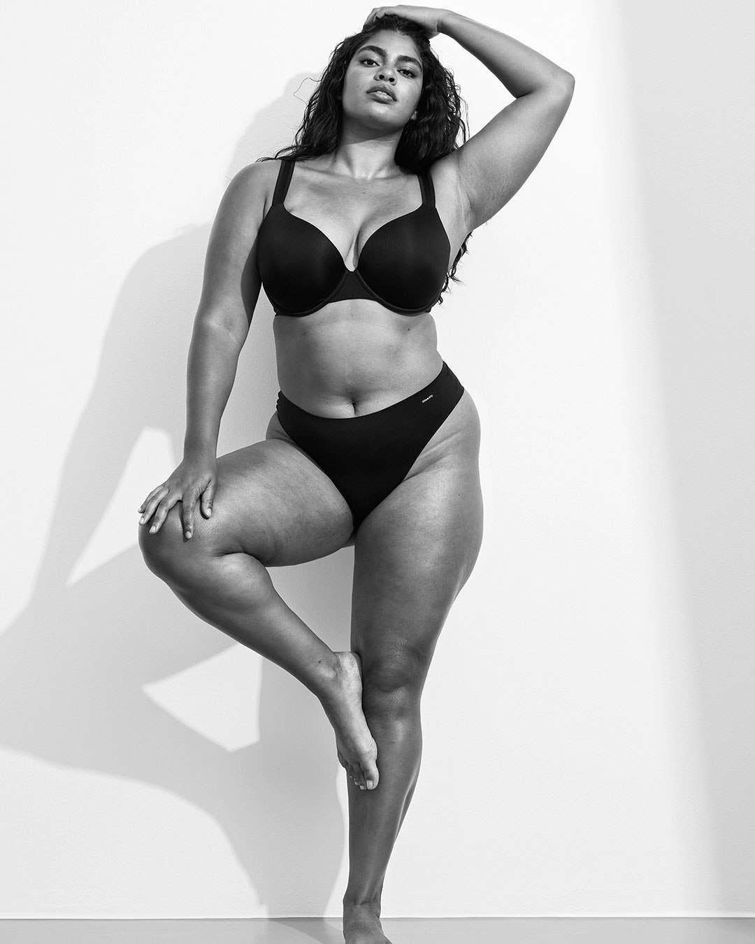 A black and white image of an woman wearing black underwear